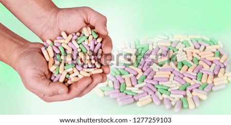 Man's hands holding colorful pills isolated on white background. Spilled different capsules on the white background. Vitamin supplements tablets