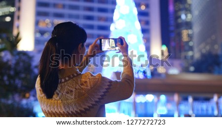 Woman take photo on cellphone in city at night