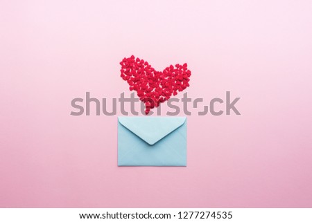 Blue letter with pink heart cartoon style from paper on cardboard background. Valentine day minimal concept Flat lay Top view