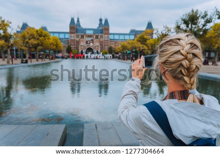 Woman tourist taking photo of the Rijksmuseum in Amsterdam on the mobile phone. Travel in Europe city trip concept Royalty-Free Stock Photo #1277304664