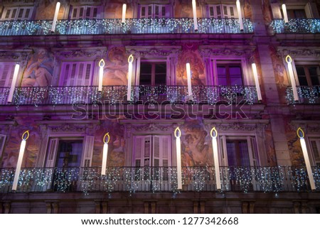 View of a Christmas decorated facade at night time in Plaza Mayor of Madrid, Spain, with balconies decorated with big candles and light shows