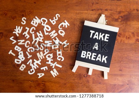 Pile of white wooden alphabet with "Take a break" text on black board. Flat lay concept for business.