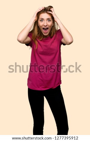 Young redhead girl with surprise and shocked facial expression on isolated yellow background