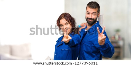 Painters smiling and showing victory sign in house