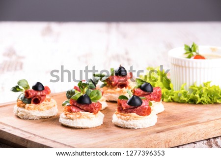 Delicious canapes with salami and spices on a wooden background. Copy space