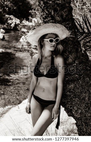 Young girl in bikini and hat have rest in palm forest of Preveli, Crete, Greece