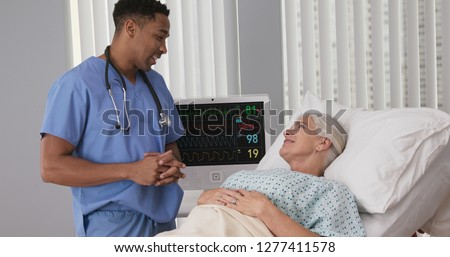 Portrait of african-american nurse assisting ill female patient lying in bed
