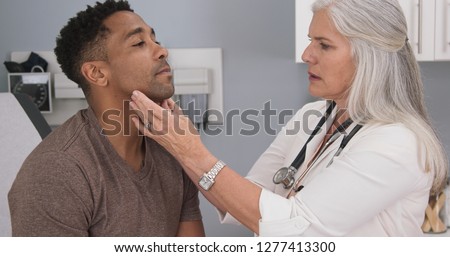 Close up of senior female doctor examining male patients neck