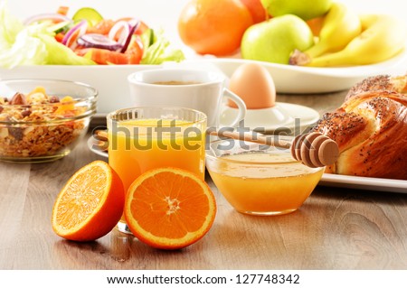 Breakfast including coffee, bread, honey, orange juice, muesli and fruits Royalty-Free Stock Photo #127748342