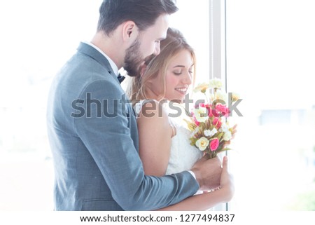 A portrait of couple love or bride in wedding studio while try to fitting suit and dress with bouquet flowers as romantic people concept