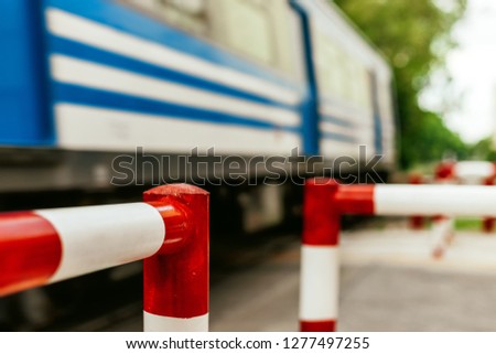 Close-up macro of railway crossing pedestrian fence with train passing quickly