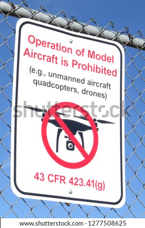 Operation of Model Aircraft Prohibited sign on chain link fence isolated on blue sky background