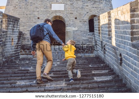 Happy cheerful joyful tourists dad and son at Great Wall of China having fun on travel smiling laughing and dancing during vacation trip in Asia. Chinese destination. Travel with children in China