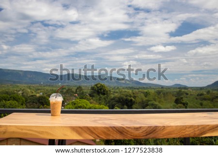 iced coffee on wooden table with mountain background 