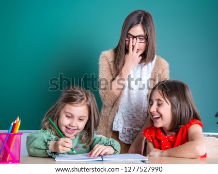 older sisters looks at her younger sister as she draws in a notebook.