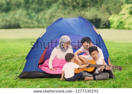 Picture of young family playing a guitar while enjoying their holiday in the campground