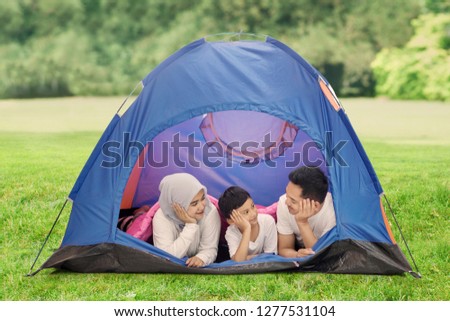 Picture of little boy camping in the forest while lying with his parents in the tent