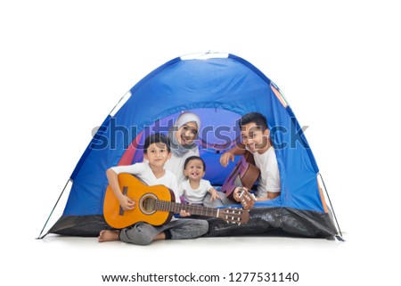 Picture of young Muslim family playing guitars in the tent while camping in the studio, isolated on white background