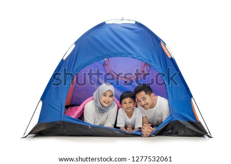 Picture of Asian family smiling at the camera while lying together in the tent, isolated on white background