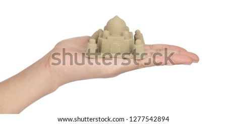 Hand holding sand sculpture of castle isolated on a white background