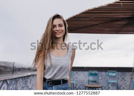 Amazing caucasian girl in casual attire posing on sky background with inspired smile. Photo of excited female model standing at roof cafe.