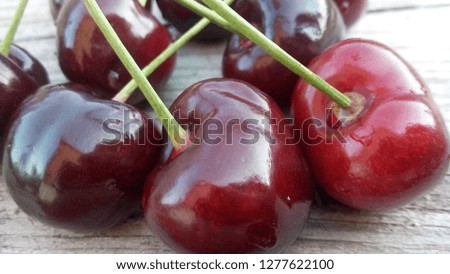 Red sweet cherry, juicy and appetizing on a wooden table, closeup.
