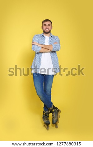 Full length portrait of young man with inline roller skates on color background