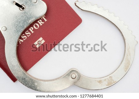 red passport on white background and handcuffs