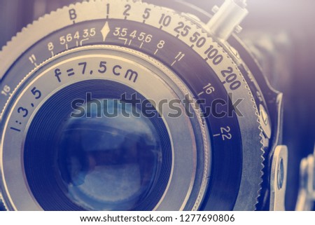 Close-up detailed photo of the optical lens of a nostalgic old retro 35mm negative film camera with f-stop and focal length number, retouched by removing out the dust and rust, vintage filter effect.