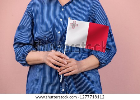 Malta flag. Close up picture of woman's hands holding a national flag of Malta.