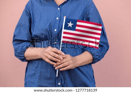Liberia flag. Close up picture of woman's hands holding a national flag of Liberia.