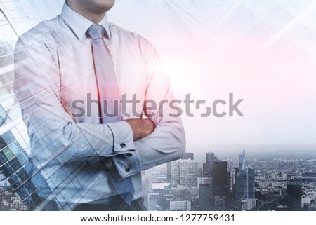 Portrait of unrecognizable businessman standing with crossed arms over modern city panorama. Business leadership concept. Toned image double exposure