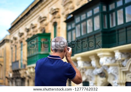 Male tourist taking photos of traditional Maltese balconies in the city center of the old town of Valetta, Malta