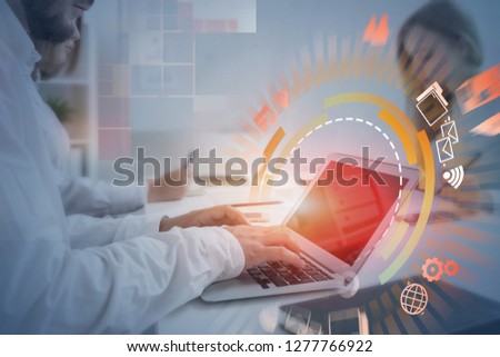 Business people working with laptop in office with business interface and hud hologram around it. Toned image double exposure