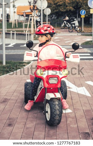 little girl in helmet on the motorbike on the playground