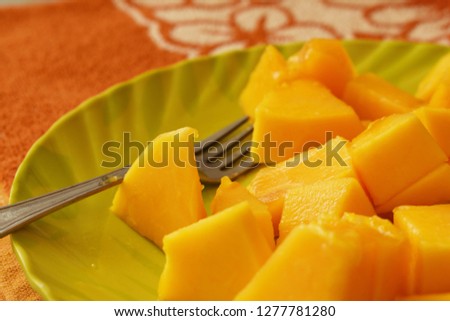Beautifully sliced pieces of papaya on a green plate with a fork 