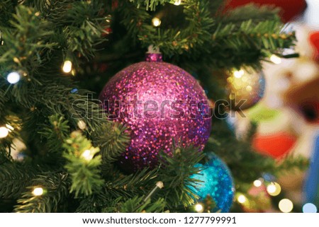Christmas card. Christmas picture. A bright sparkling pink ball on the fluffy branches of a Christmas tree. Background bokeh lights of garland. Ready Christmas background for your text. Glitter