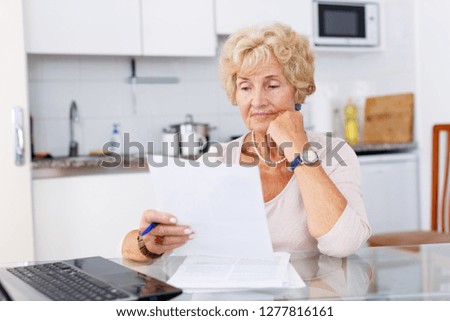 Mature woman filling up documents at kitchen table