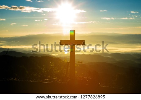cross silhouette on the mountain at sunset.