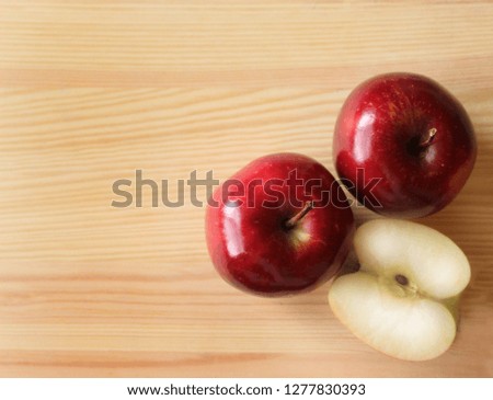 This is a close-up picture of an organic juicy red apple on a wooden surface