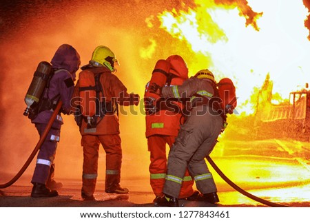The firefighters fighting a fire with a hose and water during a firefighting