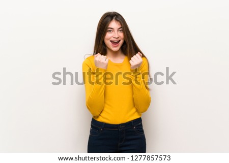 Young woman with yellow sweater celebrating a victory in winner position