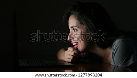 Woman reacting with shock in front of her laptop at night