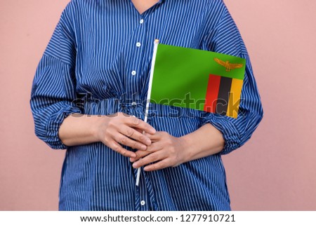 Zambia flag. Close up of woman's hands holding  a national flag of Zambia.