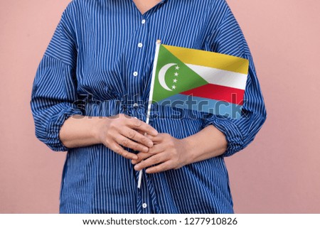 Comoros flag. Close up of woman's hands holding  a national flag of Comoros.