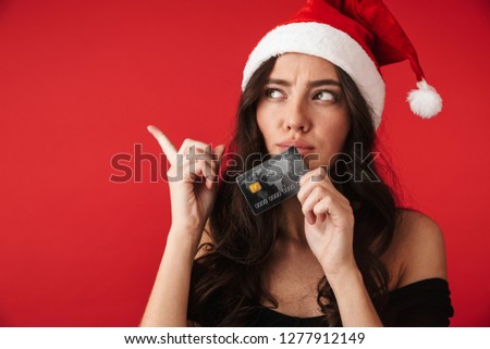 Photo of a beautiful young woman standing isolated over red wall background holding credit card.