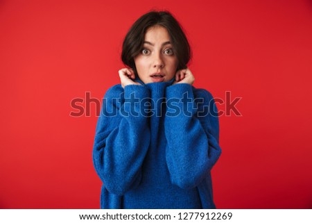 Photo of a beautiful shocked young woman posing isolated over red wall background.