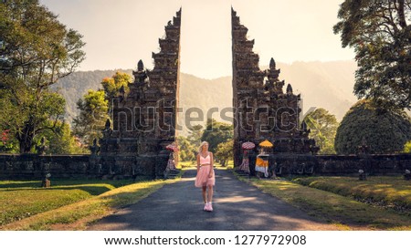 Beautiful blonde girl in pink Traditional gate Bali Indonesia temple