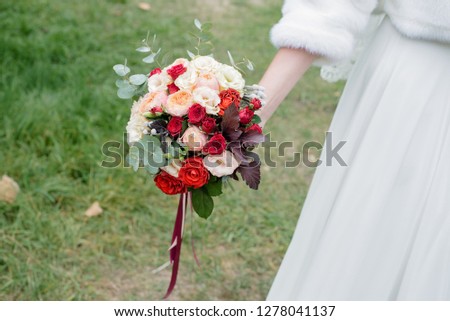 A bride in a beautiful dress is holding in hand a bouquet of bright flowers. Florist and floral background. Valentine's Day, Wedding Day, romantic day, love story