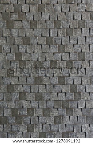 A photo of a texture of a wall surface formed with brownish gray squares. Interesting piece of architecture.